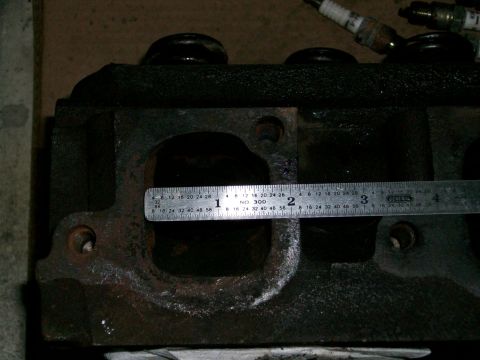 1973 Ford Ranchero - Engine cylinder head with a ruler measuring port opening, and two spark plugs visible.