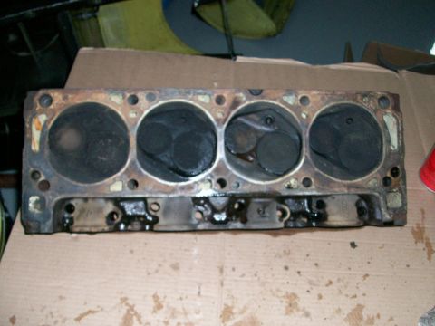 1973 Ford Ranchero - A used engine cylinder head with four visible cylinders, showing signs of wear and oil residue.