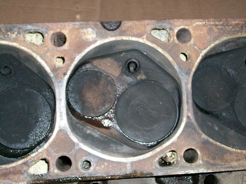 Engine cylinder head showing combustion chambers and valves, some carbon buildup visible