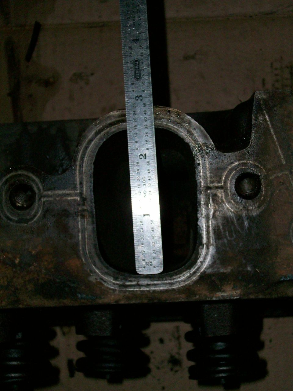 Close-up of an engine part with a ruler measuring an opening