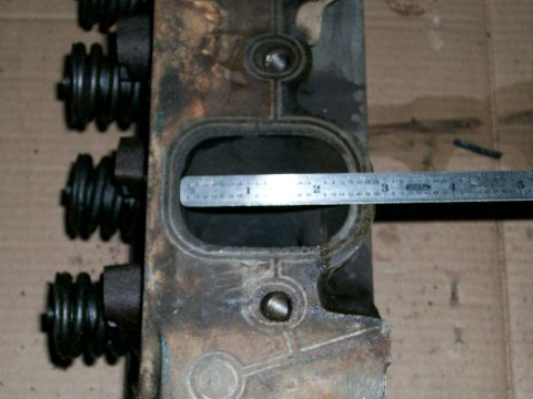 1973 Ford Ranchero - A ruler measures the intake port of a used engine cylinder head, showing valve springs on the side.