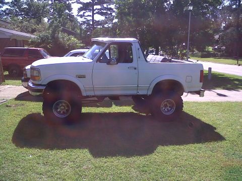 1996 Ford Bronco - This lifted 1996 Ford Bronco is parked on a grassy lawn with another vehicle visible in the background.