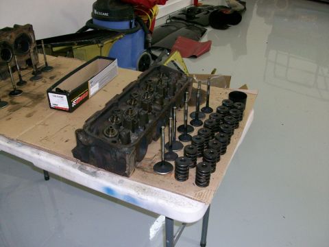 1973 Ford Ranchero - Engine cylinder heads and associated valves and springs are organized on a table, likely for a rebuild or repair.