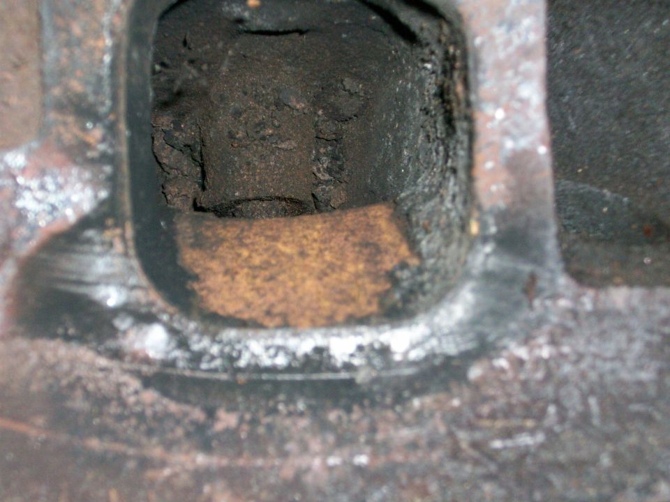 Close-up of a heavily carboned engine cylinder head port with rust