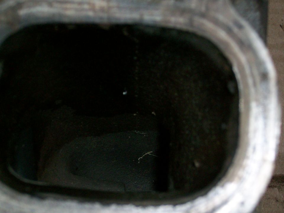 Close-up of a dark engine intake port with rough texture inside