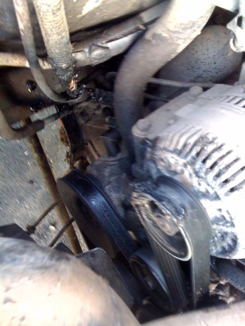 1995 Ford Bronco - Close-up view of an engine's belt and alternator, showing signs of fluid leakage.