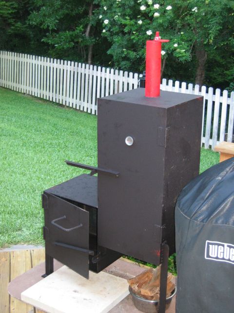 1992 Ford Bronco - A black smoker sits on a patio with a white picket fence in the background.