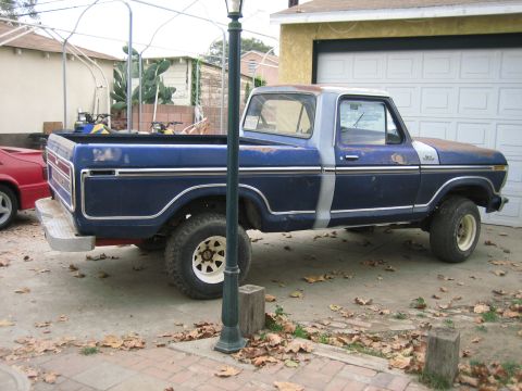 1979 Ford F-150 - This blue 1979 Ford F-150 pickup truck is parked in a driveway next to a garage.