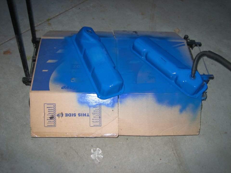 Blue painted valve covers drying on cardboard boxes