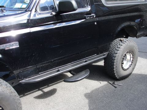 1995 Ford Bronco - Side view of a black Ford Bronco XLT with aftermarket running boards and off-road tires.