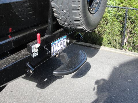 1995 Ford Bronco - The rear of a vehicle shows a custom bumper with an integrated step and a spare tire mount.