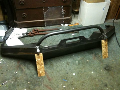 1995 Ford Bronco - A custom-fabricated steel bumper with a brush guard sits on a garage floor.
