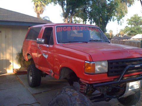 1969 Ford F-250 - This red Ford Bronco has been modified for off-road use with a lifted suspension and large tires.