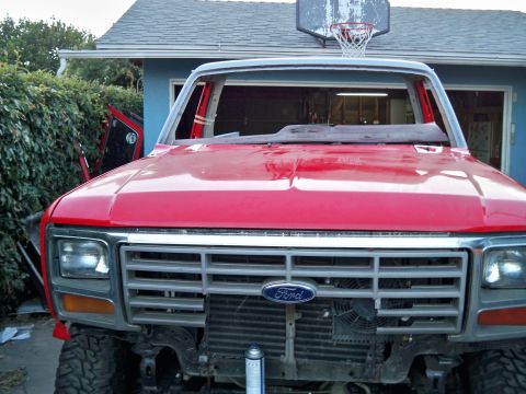 1985 Ford Bronco - Front view of a red Ford Bronco undergoing repairs, with its windshield removed.