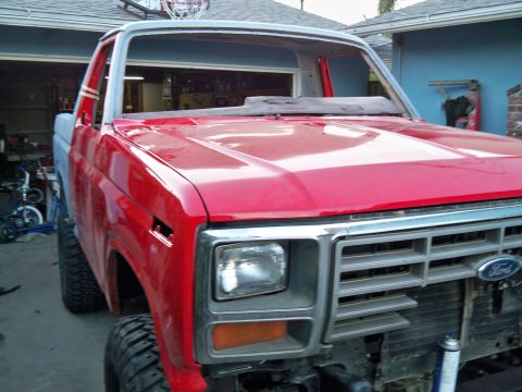 1985 Ford Bronco - This red pickup truck, likely from the early 1980s, is shown from the front while in a state of repair.