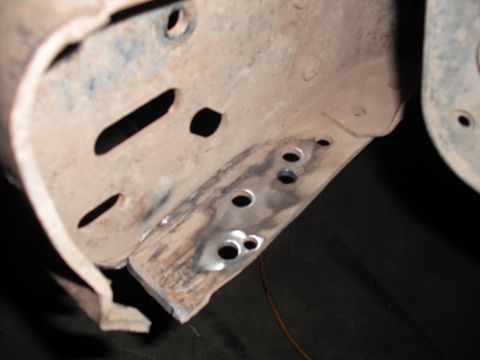 1991 Ford Bronco - Close-up view of a heavily rusted metal frame section, several drilled holes and evidence of repair work.