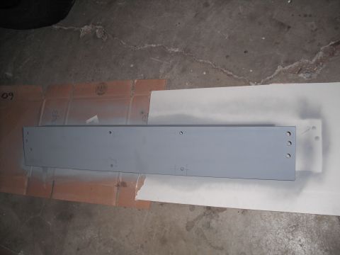 1991 Ford Bronco - A metal part is being prepped for painting, laid out on cardboard and paper on a concrete floor.