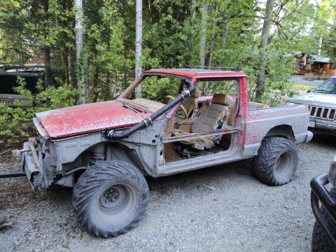 1990 Chevrolet Suburban - This heavily modified pickup truck features oversized tires and a snorkel, suggesting off-road use.