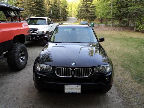 1990 Chevrolet Suburban - A black BMW X3 is parked in a driveway with two other vehicles visible.