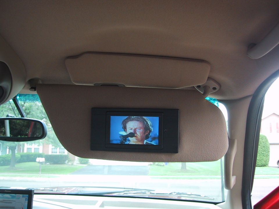 Tan sun visor with custom-mounted LCD video screen playing footage inside an SUV