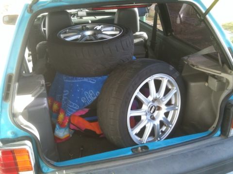 2005 Subaru Impreza - The trunk of a light blue car holds two tires and rims, with a colorful towel underneath.