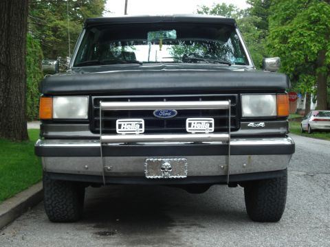 1988 Ford Bronco - Front view of a gray Ford Bronco with a chrome grille guard and auxiliary lights.