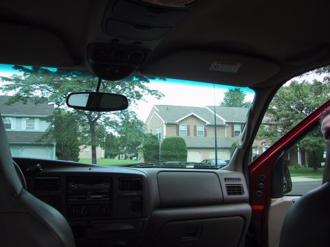 2001 Ford Excursion - The interior of a 2001 Ford Excursion shows the dashboard, center console, and passenger door, with houses visible through the windows.