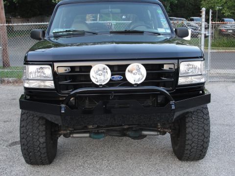 1995 Ford Bronco - Front view of a black Ford Bronco with a custom bumper and fog lights.