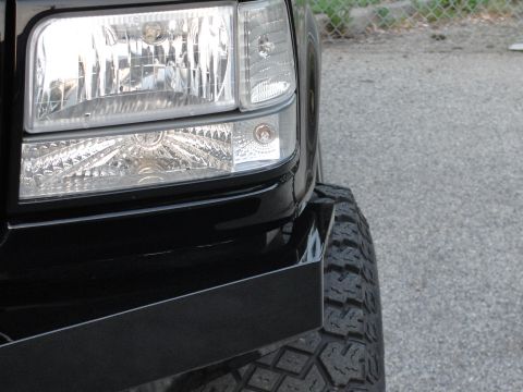 1995 Ford Bronco - Close-up of a black truck's front corner, a custom bumper and tire. Year estimated at 1997.