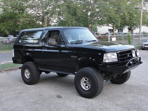 1995 Ford Bronco - A black 1995 Ford Bronco is shown from a three-quarter front angle, modified with a lift kit and aftermarket bumper.