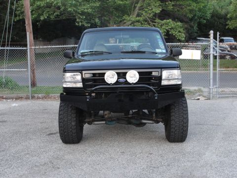 1995 Ford Bronco - Front view of a black Ford Bronco with an aftermarket bumper and auxiliary lights.