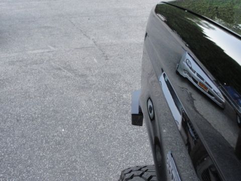 1995 Ford Bronco - Close-up of a black SUV's side panel, showing a reflection of another vehicle.