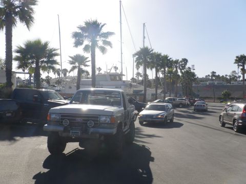 1991 Ford Bronco - This lifted Ford F-Series pickup truck is parked near a marina with sailboats in the background.