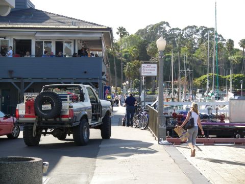 1991 Ford Bronco - A modified Ford Bronco is parked near a marina with boats in the background.