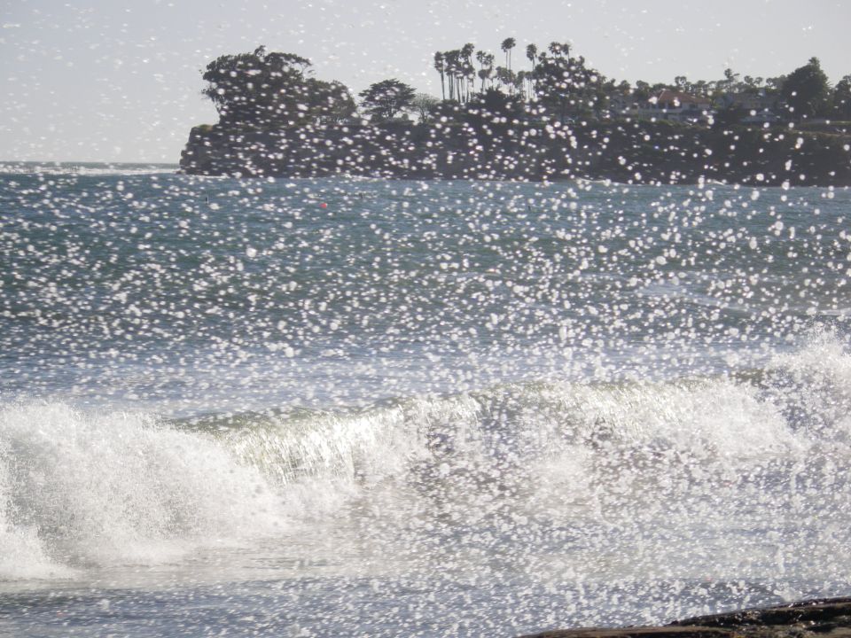 Ocean waves crashing with a distant tree-covered coastline