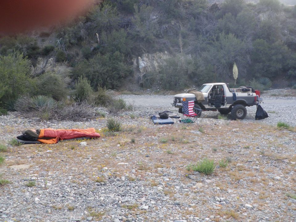 1991 Ford Bronco parked off-road with sleeping bag and chair nearby