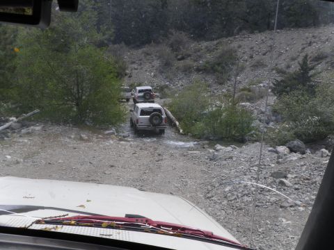 1991 Ford Bronco - Two Ford Broncos navigate a rocky stream bed on an off-road trail.