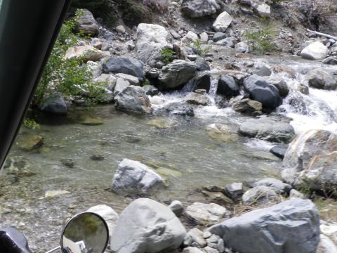 1991 Ford Bronco - Water flows over rocks in a stream bed, viewed from the perspective of someone inside a vehicle.