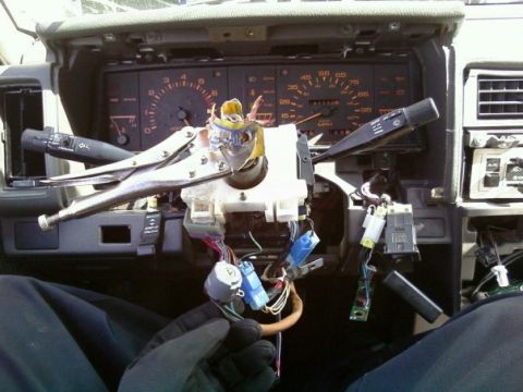 2000 Mercury Grand Marquis - The interior of a vehicle shows a disassembled dashboard with wiring exposed and vice grips clamped onto the steering column.