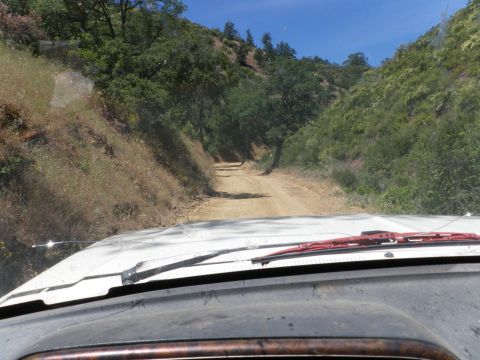 1991 Ford Bronco - Driving on a dusty, rural road through hills and trees, with a Supermotors.net logo in the lower right corner.