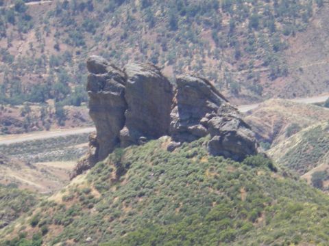 1991 Ford Bronco - A large rock formation stands on a vegetated hillside, with a road visible in the distance.
