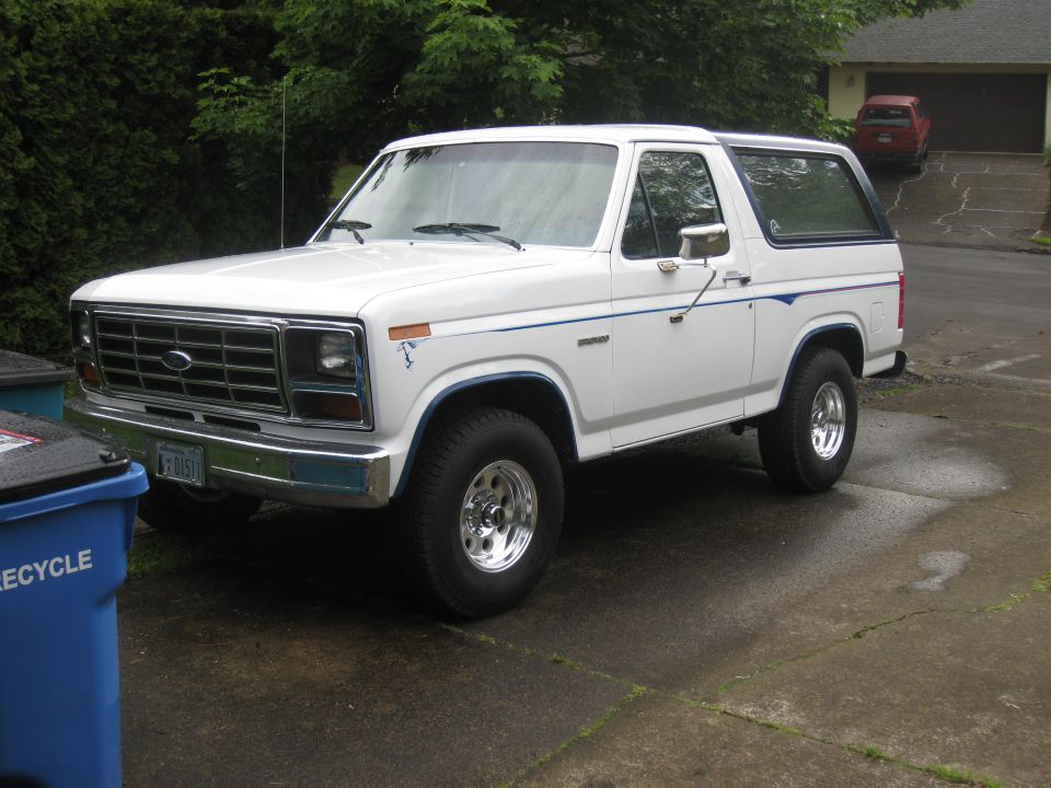 White 1985 Ford Bronco with blue pinstripes parked in a driveway