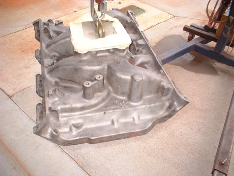 1969 Ford Torino - An engine intake manifold is shown being lifted by a hoist, with a stand visible in the background.