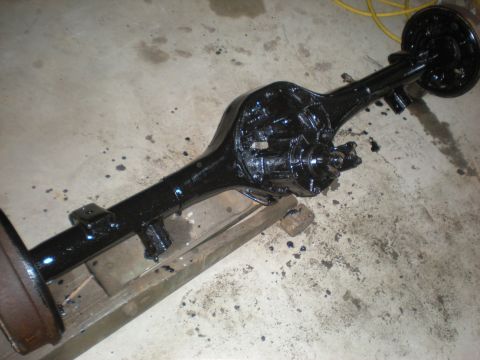 1978 Ford Bronco - A freshly painted rear axle assembly rests on wooden blocks on a concrete floor.