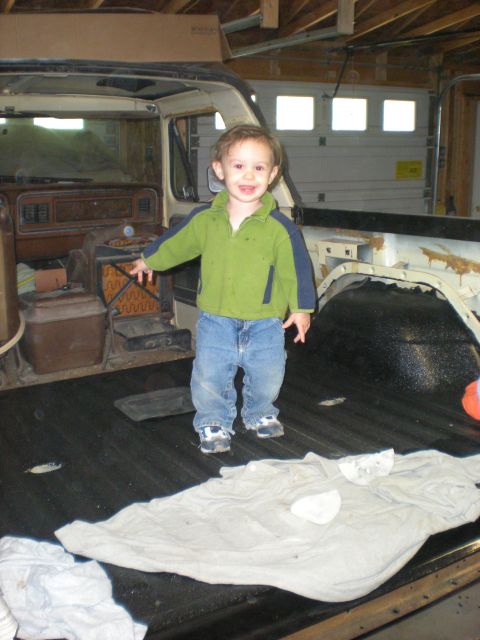 1978 Ford Bronco - A young child stands in the cargo area of a vehicle, with the interior of the cab visible behind.