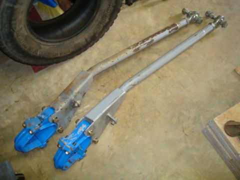 1995 Ford Bronco - Two steering linkage bars with blue ends are laid out on a concrete floor.