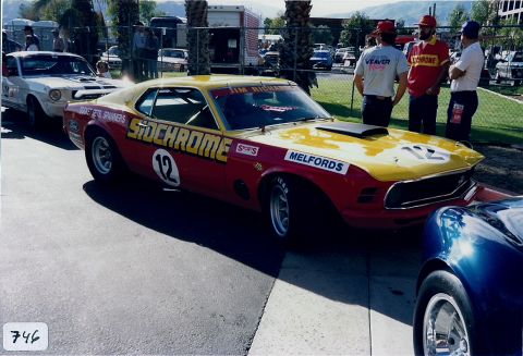 1973 Ford Mustang - A vintage race car, possibly a 1970 Ford Mustang, is seen at a track event with other vehicles present.