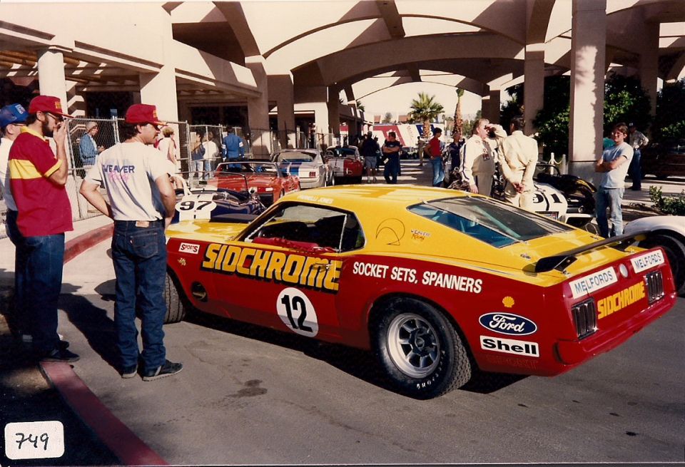 Red and yellow 1970s racing car with "SIDCHROME" livery, number 12, and "Ford" and "Shell" decals