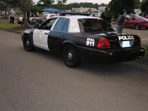 1991 Ford LTD Crown Victoria - Rear three-quarter view of a black-and-white Ford Crown Victoria police car marked POLICE and Dial 911 at an outdoor event.