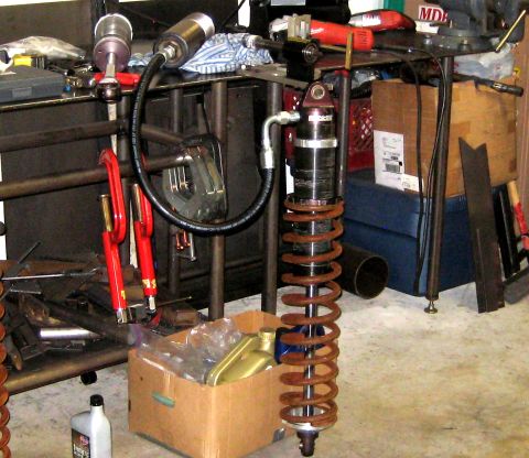 1996 Ford Bronco - A coilover shock absorber assembly with a hydraulic line is shown, surrounded by tools and parts.